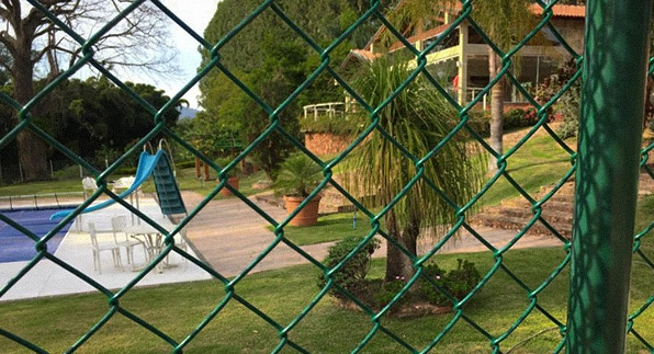 Imagem mostrando a aplicação das telas aramadas, galvanizadas e revestidas em PVC verde em um quintal de uma casa com piscina