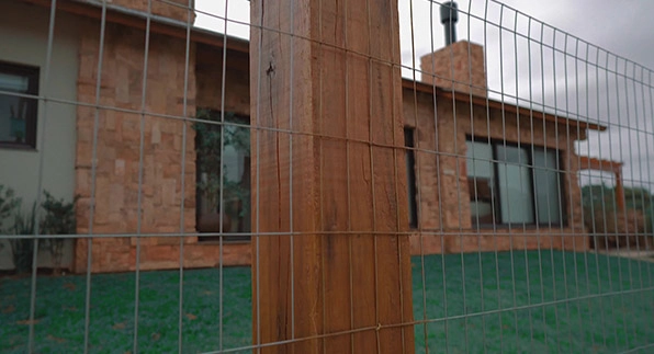 Imagem mostrando a aplicação da tela residência em um quintal de uma casa com tijolos marrons e com janelas de vidros compridas