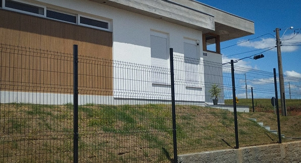 Imagem mostrando uma casa nas cores branca e marrom segura e protegida, pois esta utilizando as telas para casa vendidas pela Casa das Cercas