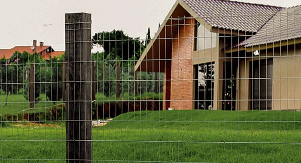 Imagem mostrando a aplicação da tela residência em um quintal de uma casa com tijolos marrons e com janelas de vidros compridas